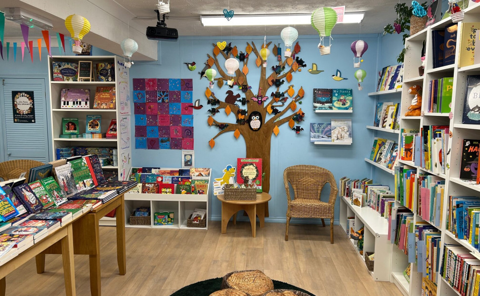 The childrens section of the bookshop with a painted tree on the far wall